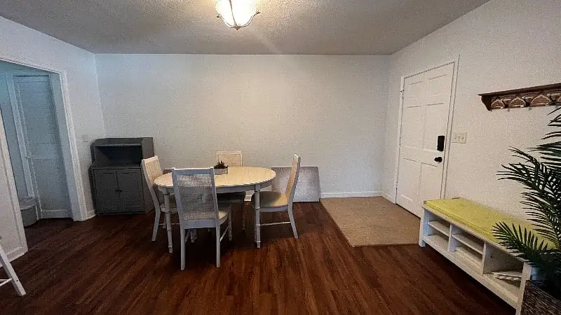 Dining area with a round table and four chairs, next to the front door