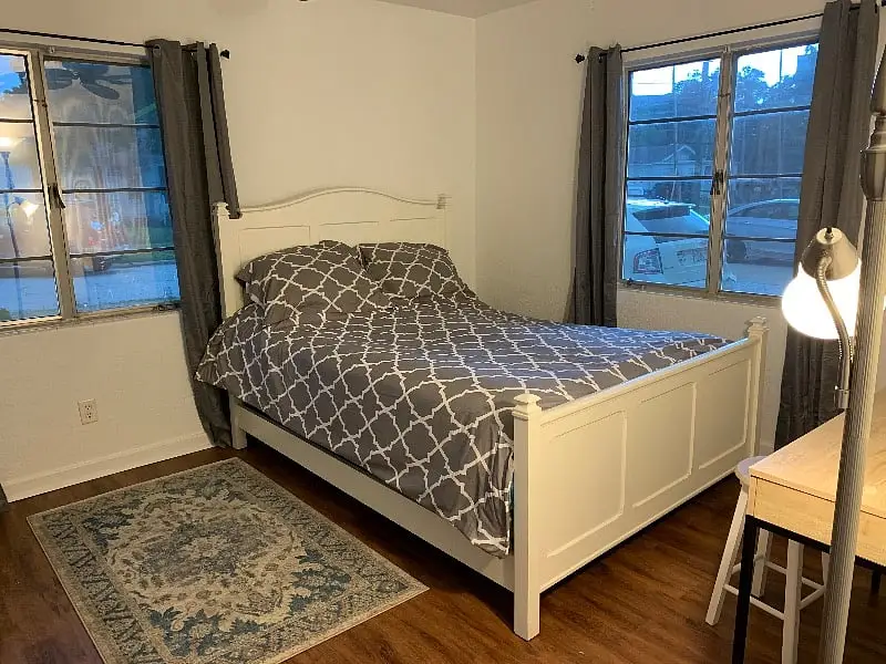 Bedroom with a queen bed in a white frame, a bedside lamp and a patterned rug