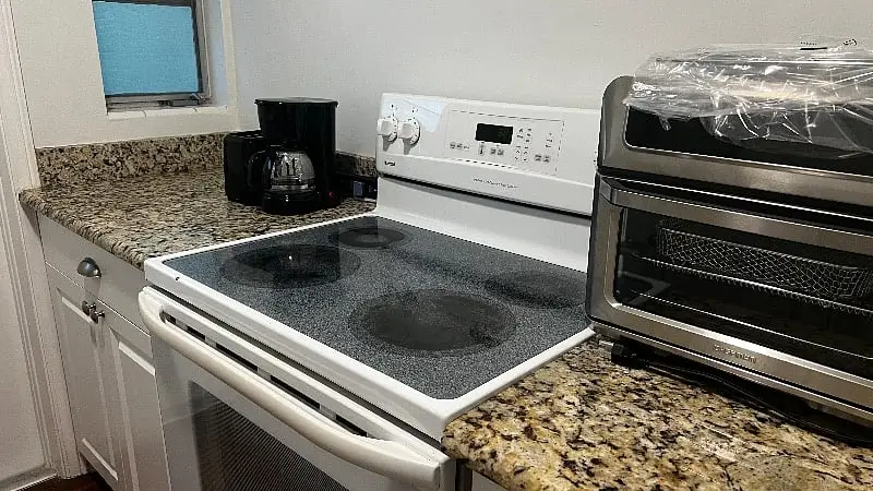 Kitchen with an electric range, granite counters, a coffee maker and a countertop oven