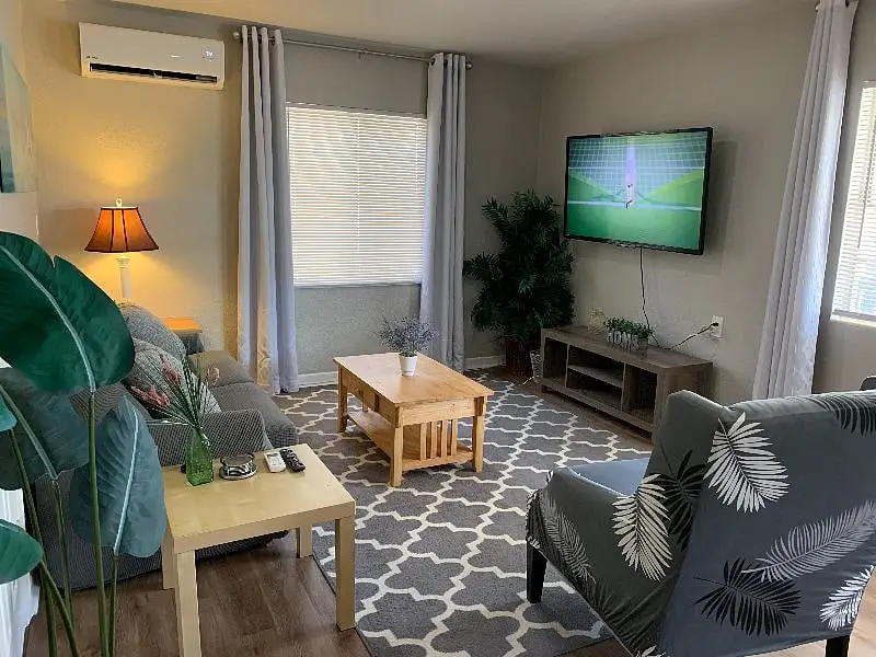 Living room with a grey sofa, a floor lamp and a television mounted above the console