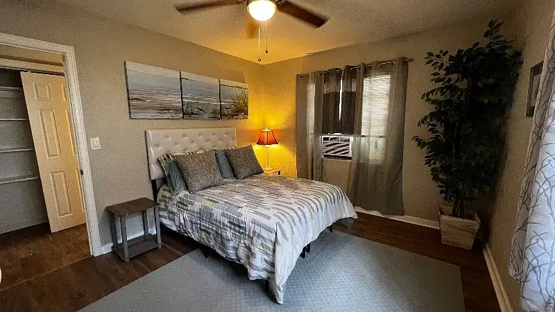 Bedroom with a queen bed, an upholstered headboard and a bedside lamp