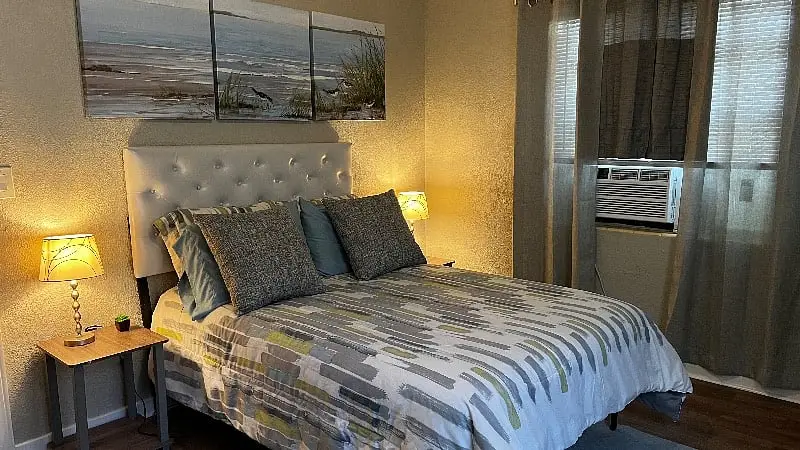 Bedroom with a queen bed and a window air-conditioning unit above the nightstand