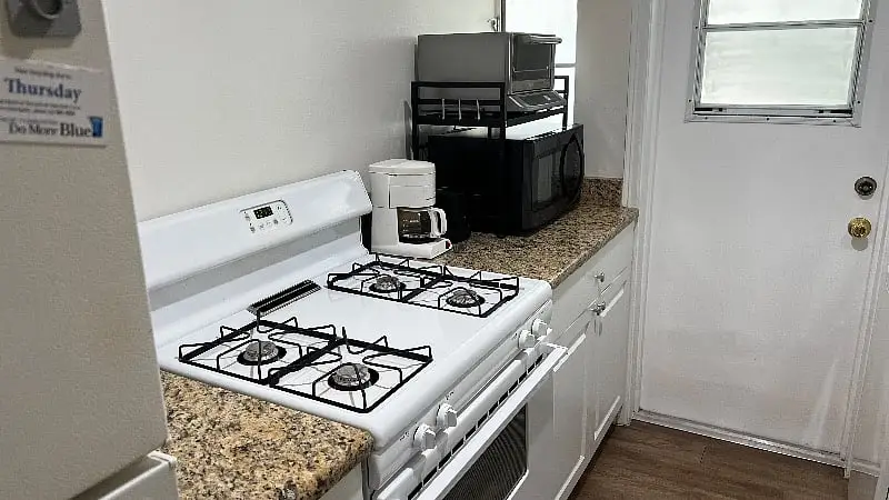 Kitchen with a gas range, granite counters, a microwave and a coffee maker