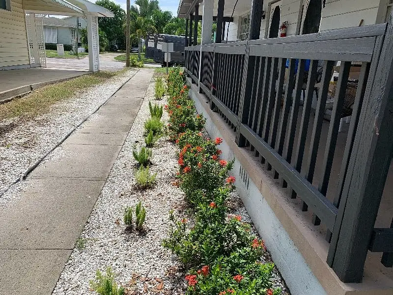 Paved walkway and railing running beside a planting bed