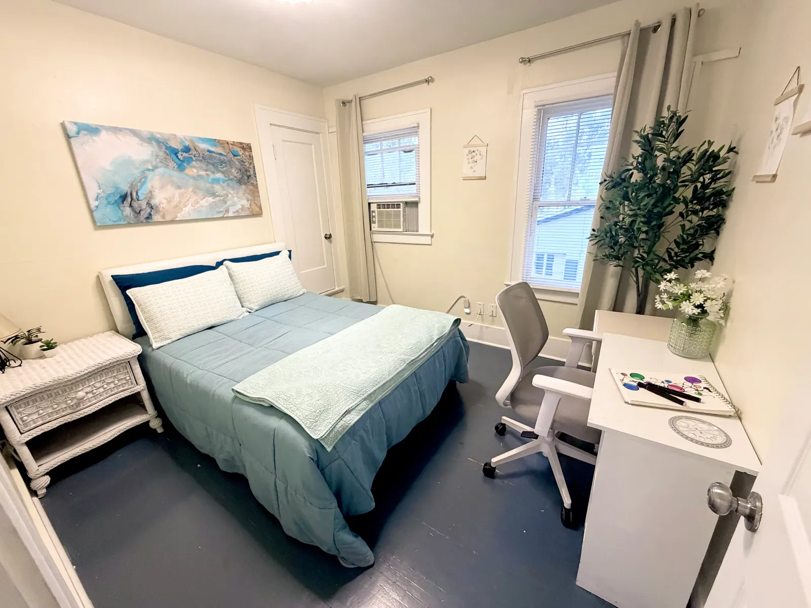Second bedroom with a queen bed, a nightstand, a window air-conditioning unit, and a desk with an office chair beneath a second window