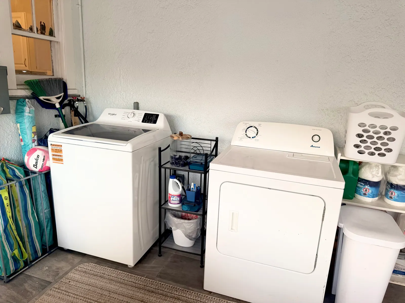 A washer and dryer side by side on the enclosed porch, with a shelf of detergent and a laundry basket