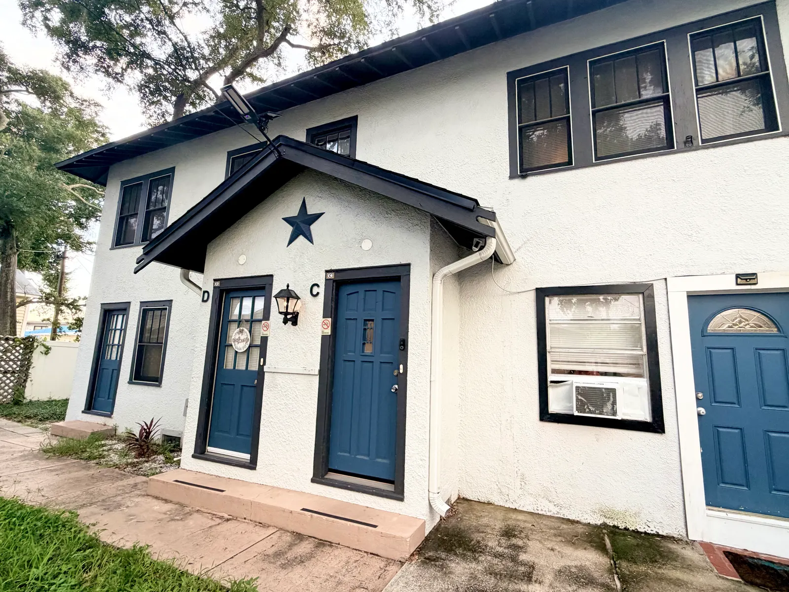 Exterior of the two-storey building, showing Unit C's own front door beside the neighbouring unit's, under a gabled porch roof