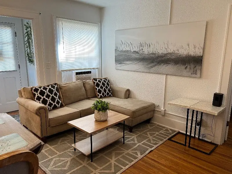Living room with a tan sofa, a low coffee table and framed artwork above it
