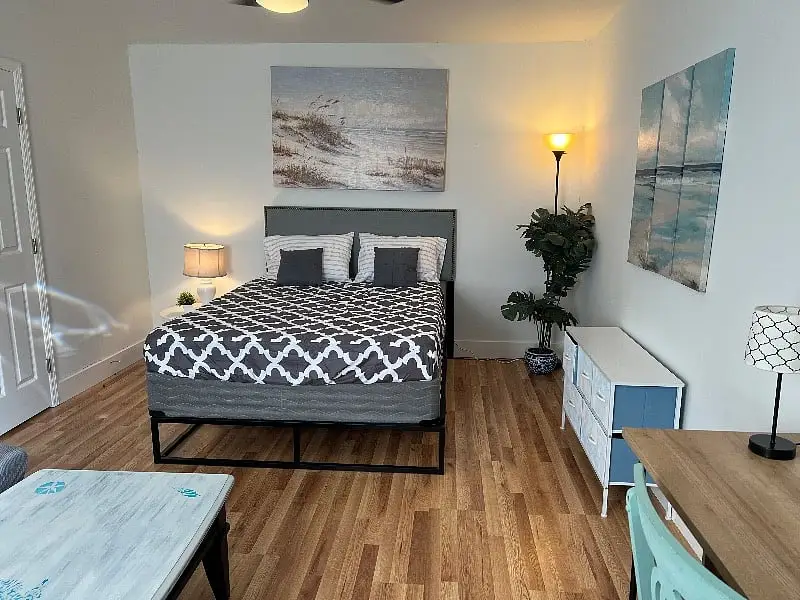 Bedroom with a queen bed, artwork above the headboard and wood floors