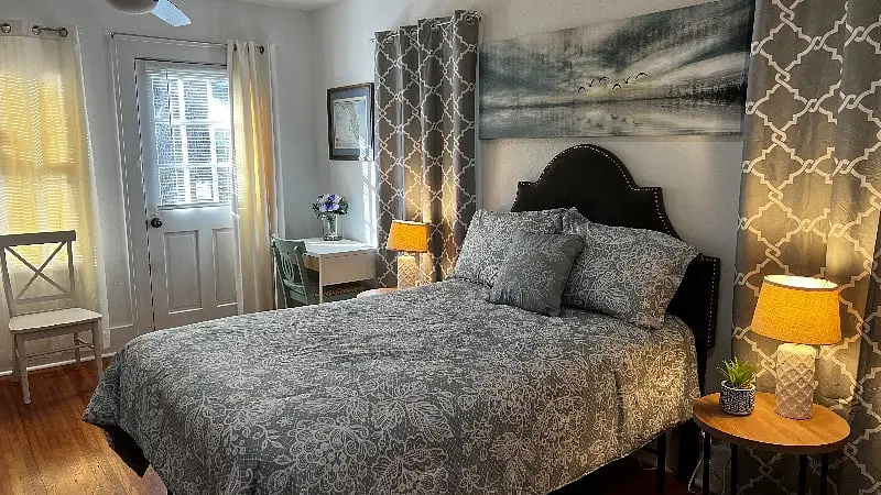 Second bedroom with a queen bed beside a curtained window