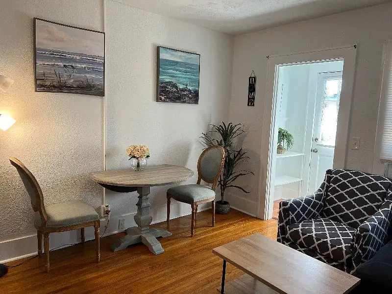 Dining table and chairs beneath a framed print, looking through to the next room